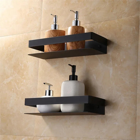 Black wall-mounted shelves with decorative bottles against a beige tiled wall.