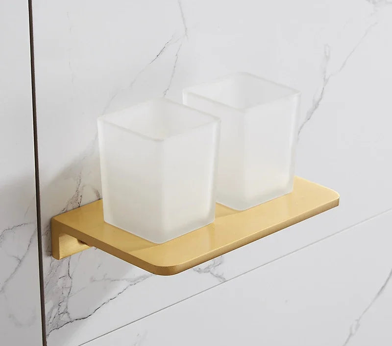 Gold soap dish with three white soap bars on a tiled bathroom wall.