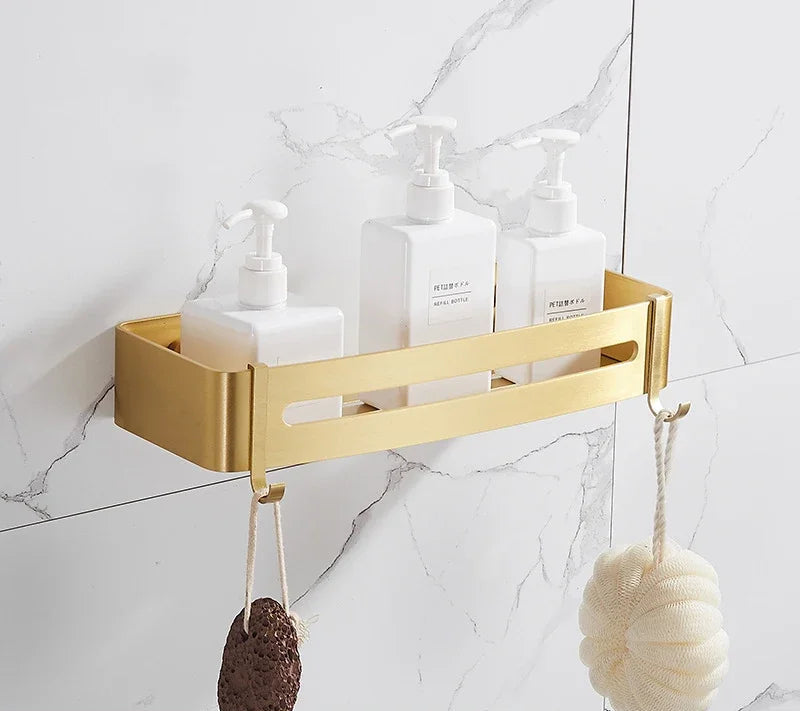 Gold rectangular shower caddy with toiletries on a marble bathroom wall.