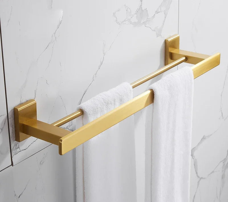 Gold towel rack with white towels on a marble wall