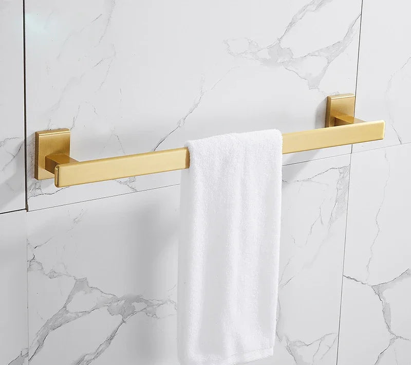 Gold towel bar with a white towel on a marble bathroom wall