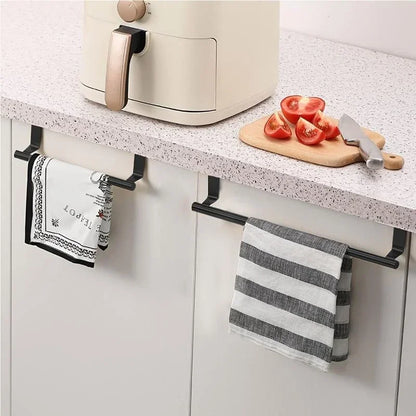Towel racks mounted on a kitchen cabinet with towels hanging on them, next to a cutting board with tomatoes and a knife.