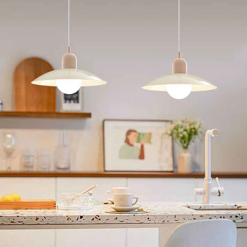 Two pendant lights hanging above a kitchen counter with a cup and saucer on a plate.
