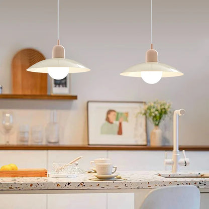 Two pendant lights hanging above a kitchen counter with a cup and saucer on a plate.