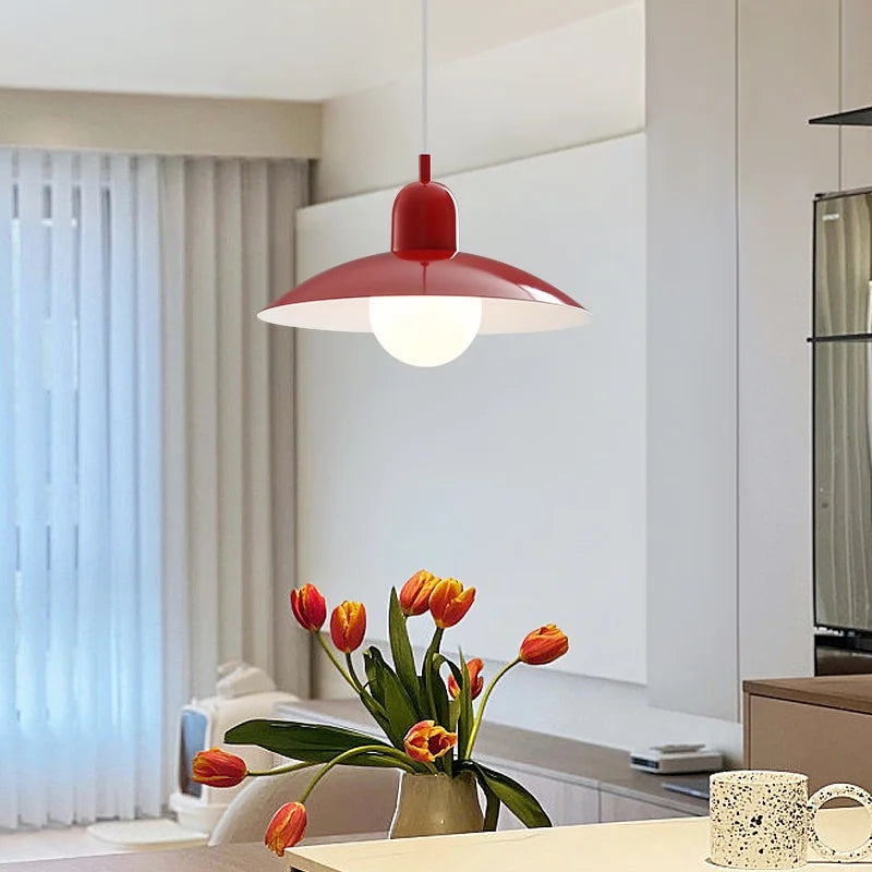 Red pendant light hanging above a table with a vase of tulips in a modern room.