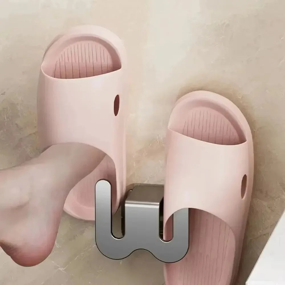 Pink slippers with a metallic 'W' logo on a neutral background
