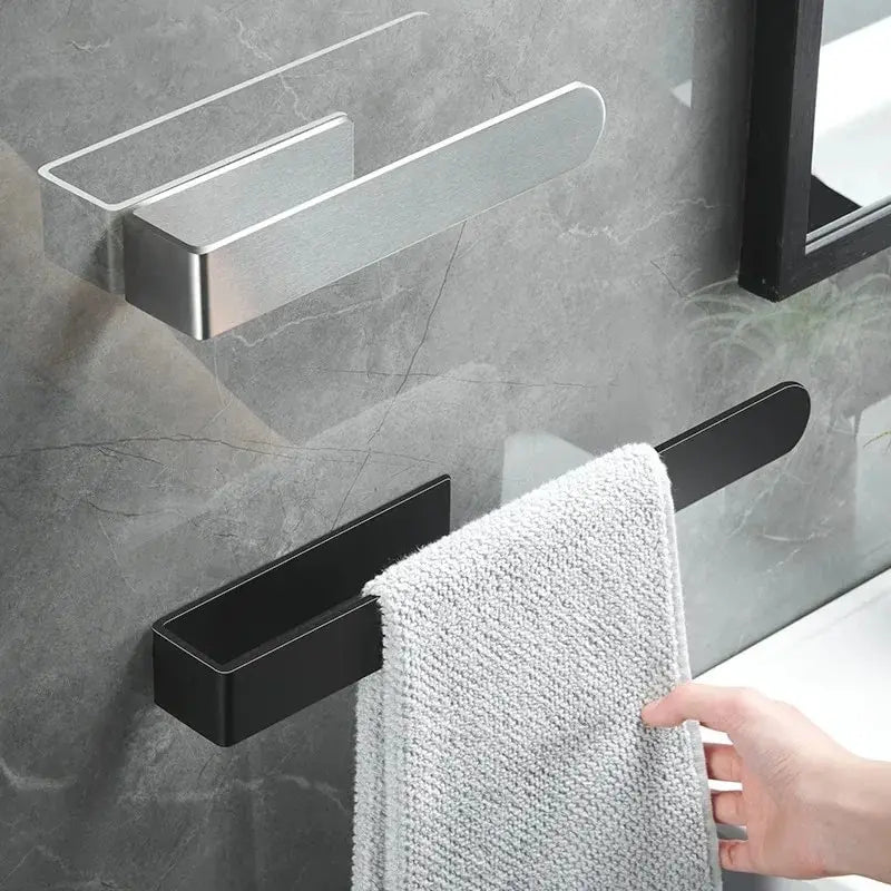 Black towel rack with a white towel on a gray tiled wall.